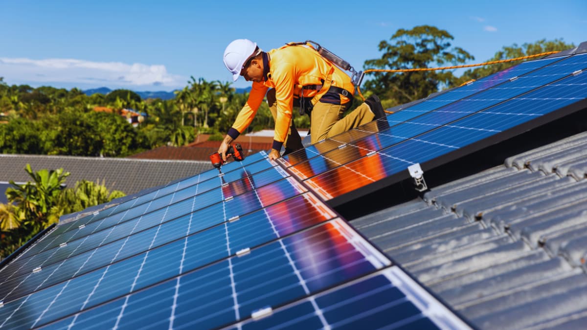 Installateur monteert zonnepanelen op een schuin dak met valbeveiliging