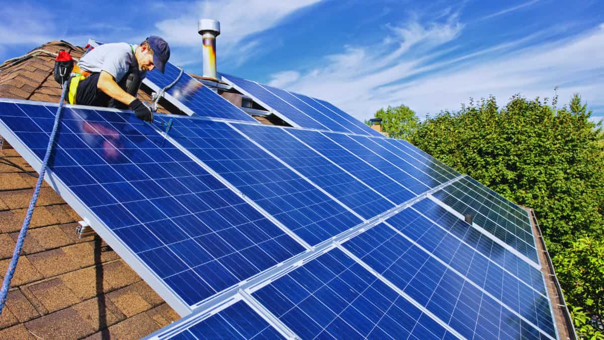 Installateur sluit de bekabeling van zonnepanelen aan op een schuin dak